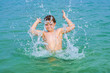 handsome boy enjoys sputtering with his hand in the tropical oce