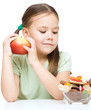 Little girl choosing between apples and sweets