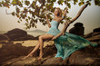 Beautiful Woman In Blue Fluttering Dress Swinging On A Beach Swi