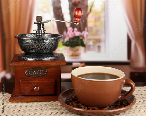 Photo: cup of coffee with scarf and coffee mill on table in room cup of coffee with scarf and coffee mill on table in room