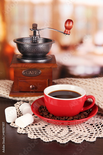 Photo: cup of coffee with scarf and coffee mill on table in room cup of coffee with scarf and coffee mill on table in room