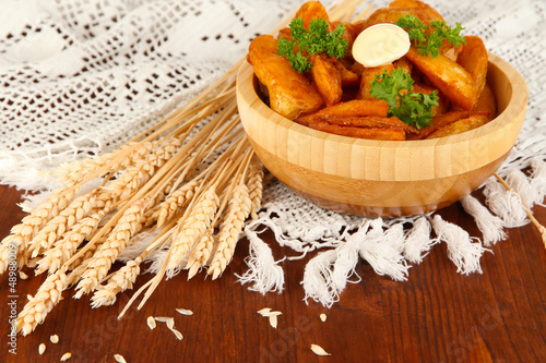 Photo: Appetizing village potatoes in bowl on wooden table close-up Appetizing village potatoes in bowl on wooden table close-up