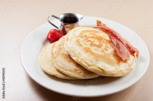 Photo: Pancakes and bacon with syrup on pink table Pancakes and bacon with syrup on pink table