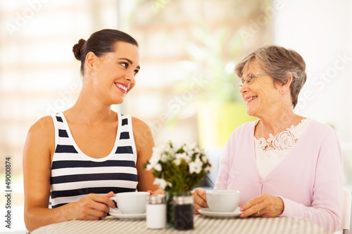 Photo: young woman visiting senior mother and having coffee together young woman visiting senior mother and having coffee together