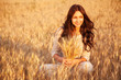 Beautiful brunette lady in wheat field at sunset