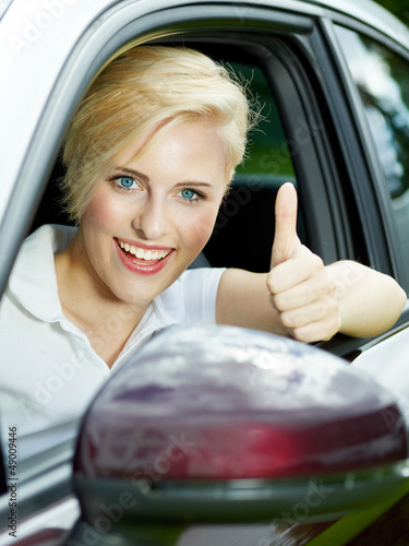 Photo: Beautiful 20s driving a red car and shows thumb up Beautiful 20s driving a red car and shows thumb up