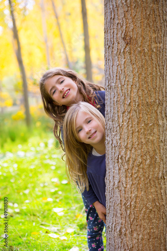 Photo: Autumn sister kid girls playing in forest trunk outdoor Autumn sister kid girls playing in forest trunk outdoor