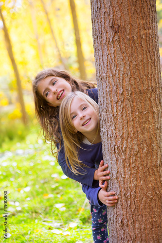 Photo: Autumn sister kid girls playing in forest trunk outdoor Autumn sister kid girls playing in forest trunk outdoor