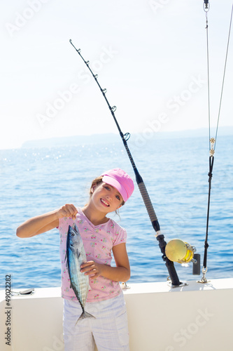 Photo: child little girl fishing in boat holding little tunny fish catc child little girl fishing in boat holding little tunny fish catc