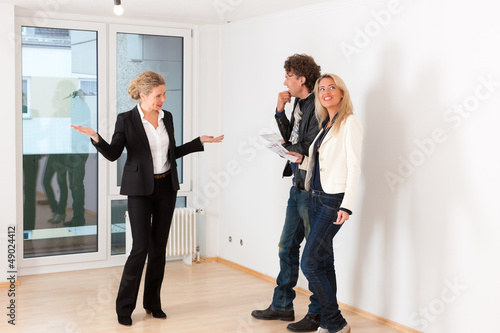 Photo: Young couple looking for real estate with female realtor Young couple looking for real estate with female realtor