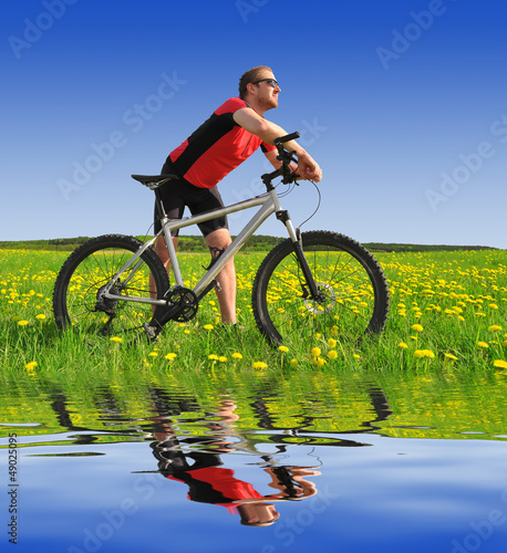 Photo: biker with the mountain bike in the dandelion field biker with the mountain bike in the dandelion field