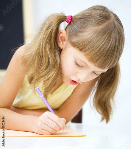 Photo: Little girl is writing using a pen Little girl is writing using a pen