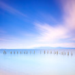 Poles and soft water on sea landscape. Long exposure.