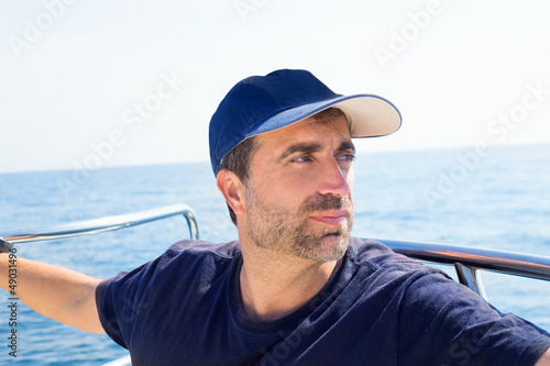 Photo: Sailor man at boat bow with cap looking away the sea Sailor man at boat bow with cap looking away the sea