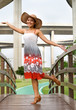 Woman in dress walking on footbridge.