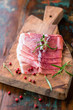 Prosciutto Crudo with rosemary on wooden chopping board