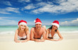 Photo: Happy friends in santa hats on the beach. Christmas vacation Happy friends in santa hats on the beach. Christmas vacation