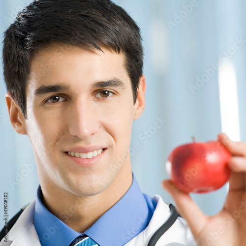 Photo: Smiling doctor with apple, at office Smiling doctor with apple, at office