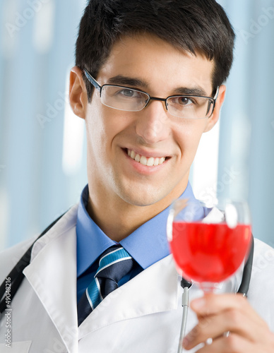 Photo: Smiling young doctor with redwine Smiling young doctor with redwine