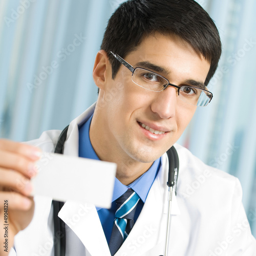 Photo: Doctor showing business card, at office Doctor showing business card, at office
