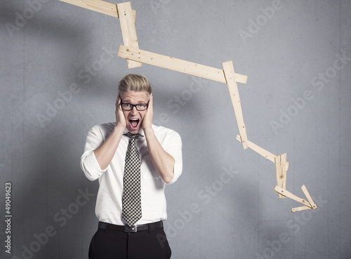 Photo: Devastated businessman shouting in front of graph pointing down. Devastated businessman shouting in front of graph pointing down.