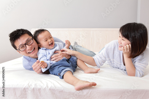 Photo: happy family playing on white bed happy family playing on white bed