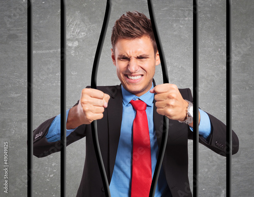 Photo: businessman bending the bars of his prison businessman bending the bars of his prison