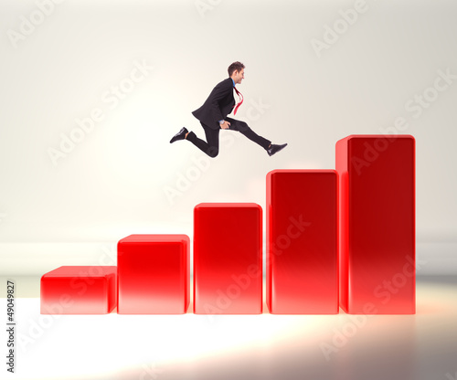 Photo: business man jumping on a 3d graph business man jumping on a 3d graph