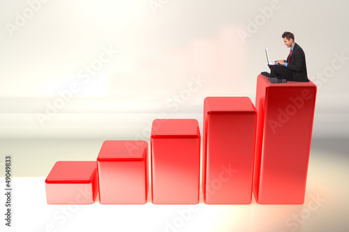 Photo: business man working on his laptop computer on graph business man working on his laptop computer on graph