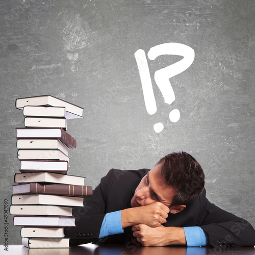 Photo: tired law student looking at a big pile of books tired law student looking at a big pile of books