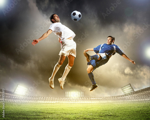 Photo: two football players striking the ball two football players striking the ball