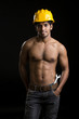 Foto: Healthy muscular young man with yellow helmet on black Healthy muscular young man with yellow helmet on black
