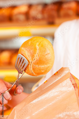Photo: Salesperson is packing bread in bakery Salesperson is packing bread in bakery