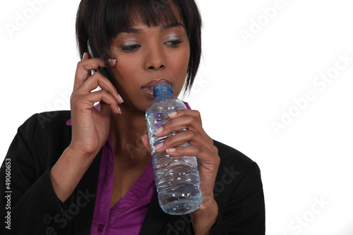 Photo: Woman with mobile phone drinking water Woman with mobile phone drinking water
