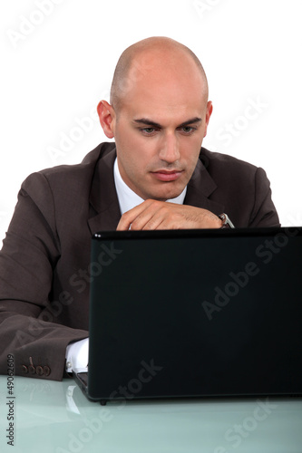Photo: Bald office worker sat at computer Bald office worker sat at computer