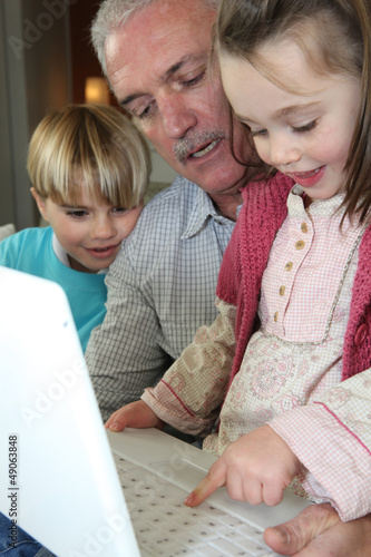Photo: grandfather and grandchildren with laptop grandfather and grandchildren with laptop