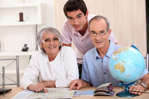 Photo: Young man and senior couple seeking a route on a map Young man and senior couple seeking a route on a map