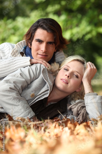 Photo: Young couple laying in autumnal leaves Young couple laying in autumnal leaves
