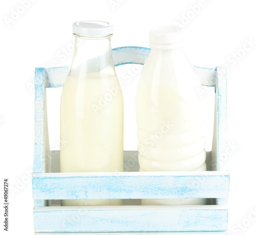 Photo: Milk in bottles in wooden box isolated on white Milk in bottles in wooden box isolated on white