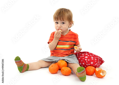 Photo: cute little boy eating tangerines, isolated on white cute little boy eating tangerines, isolated on white