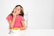 Tired sleepy young child with bowl of breakfast cereal