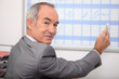 Grey haired man writing on calendar