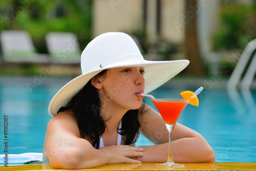 Photo: girl with a cocktail at the edge of the swimming pool girl with a cocktail at the edge of the swimming pool
