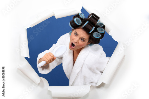 Photo: Woman wearing hair rollers, singing into brush Woman wearing hair rollers, singing into brush
