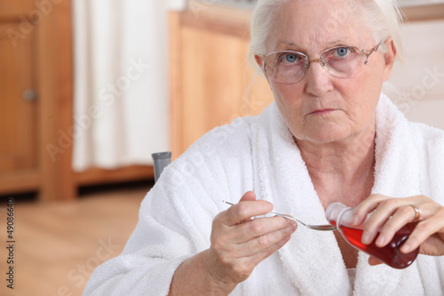 Photo: Elderly lady taking medication in kitchen Elderly lady taking medication in kitchen