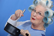 Cheeky older woman in rollers whisking sauce