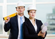 Photo: Two contractors in white hard hats keeping level and blueprints Two contractors in white hard hats keeping level and blueprints