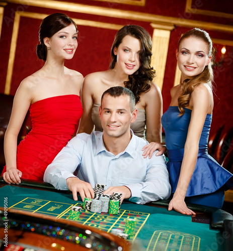 Photo: Man surrounded by women gambles roulette at the casino Man surrounded by women gambles roulette at the casino