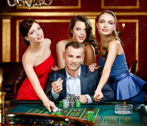Photo: Man surrounded by women plays roulette at the casino club Man surrounded by women plays roulette at the casino club