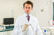 Dentist in his surgery, he holds a drill